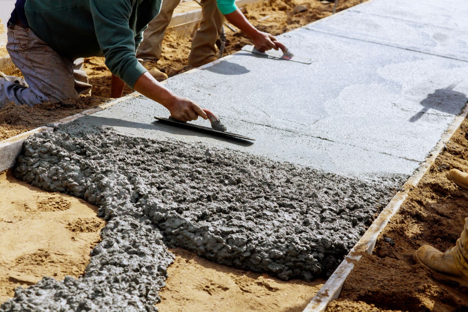Crew screeding and troweling a freshly poured concrete slab