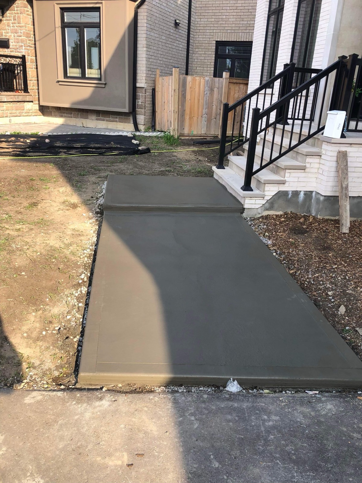 Freshly poured concrete front walkway beside porch steps